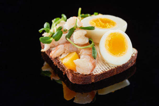 close up of rye bread with delicious shrimps on smorrebrod sandwich on black  - Fotó, kép