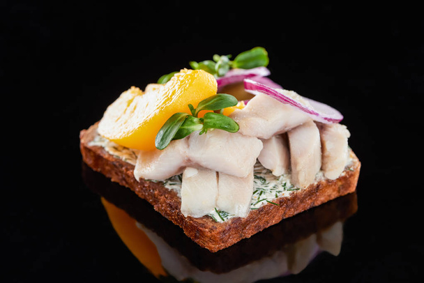 close up de peixe de arenque e pêssegos enlatados em sanduíche de smorrebrod dinamarquês preparado em preto
  - Foto, Imagem