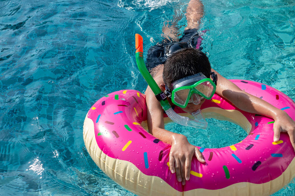 Vacaciones de verano - Niño feliz en máscaras faciales y tubos en la piscina
. - Foto, imagen