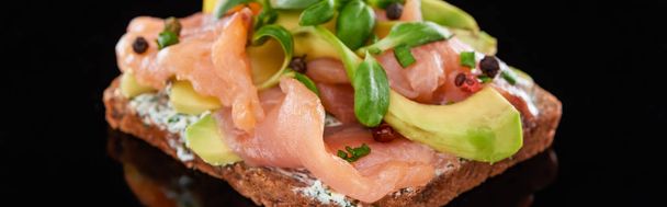 colpo panoramico di avocado vicino al salmone su panino danese smorrebrod su nero
  - Foto, immagini