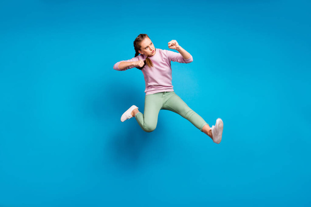 Full body profile side photo of concentrated funky youth girl jump train her fighting skills kick leg enemy wear modern clothes sweater isolated over blue color background - Foto, immagini