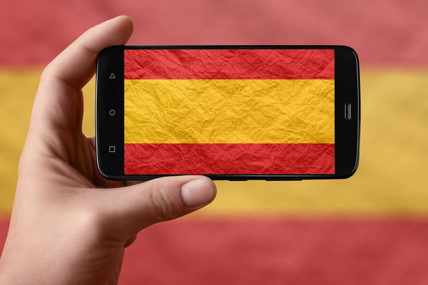 Σημαία Ισπανίας στην οθόνη του τηλεφώνου. Smartphone στο χέρι φωτογράφηση σημαία.  - Φωτογραφία, εικόνα