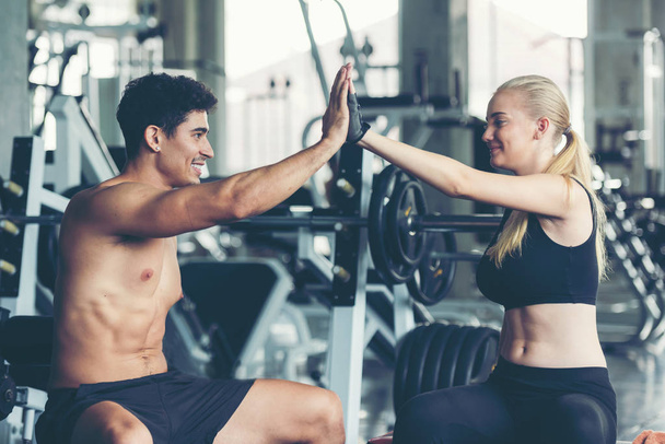 Smiling couple giving high five after success exercise  with dumbbell at the gym workout for healthy care and body slim.  Fitness instructor exercising the fitness. Diet and Healthy sport Concept - Valokuva, kuva