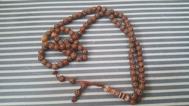 Belle perline di preghiera in legno o rosario con sfondo a strisce
 - Foto, immagini
