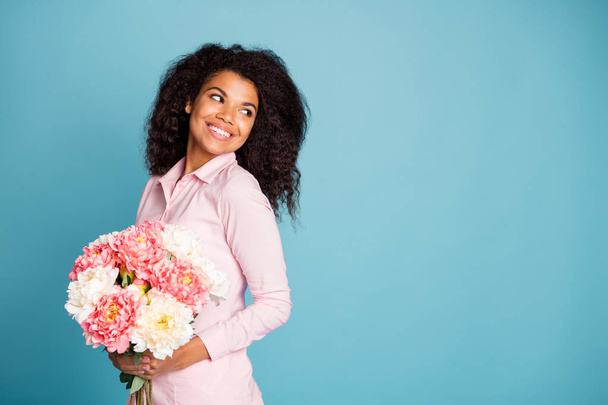 Photo of amazing wavy dark skin model lady holding big fresh flowers bunch enjoy unexpected surprise 8 march morning wear pink shirt isolated blue color background - Fotoğraf, Görsel