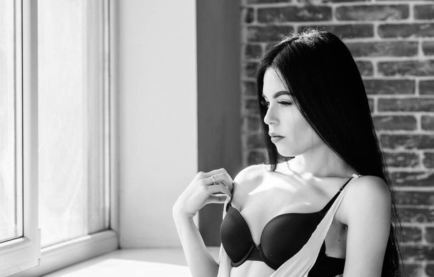 Sexual costume for pleasure. Passionate mysterious lover. Enjoying morning sunlight. Sensual girl sexy breasts relaxing near windowsill. Attractive female sexy lingerie at home. Stunning sexuality - Fotografie, Obrázek