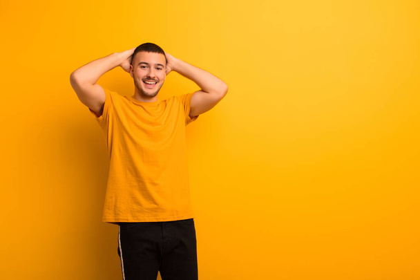 young handsome man looking happy, carefree, friendly and relaxed enjoying life and success, with a positive attitude against flat background - Photo, Image