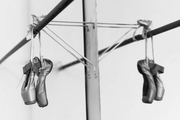 Ballet shoes hanging on the practice bar - 写真・画像