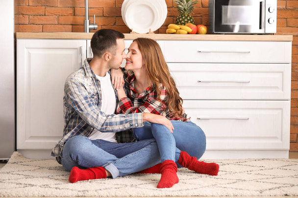 Onnellinen nuori pari istuu lattialla keittiössä
 - Valokuva, kuva