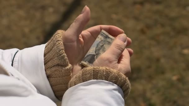 Oudere vrouw houdt dollar hand, pensioen armoede, sociale onzekerheid, begroting - Video