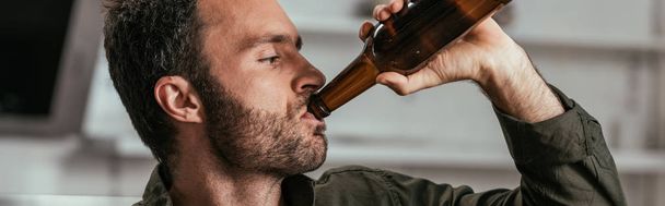 Panoramic shot of man drinking beer from bottle - Фото, изображение
