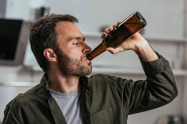 Алкоголик пьет пиво из бутылки.
 - Фото, изображение