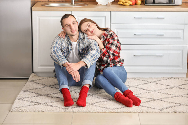 Onnellinen nuori pari istuu lattialla keittiössä
 - Valokuva, kuva