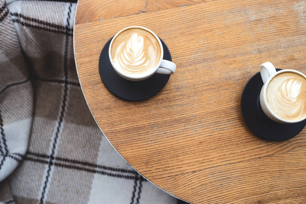 Two cups of cappuccino on a wooden cafe or coffee shop table. Top view, flat lay. - Photo, Image