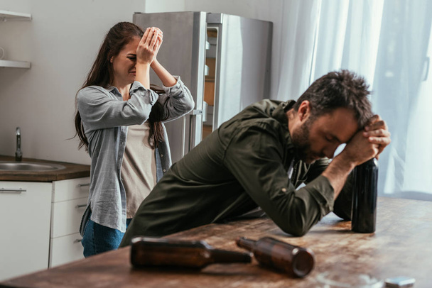 Valikoiva painopiste itkevän naisen alkoholista riippuvainen aviomies keittiössä
 - Valokuva, kuva