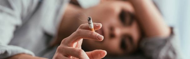 Enfoque selectivo de la mujer sosteniendo el cigarrillo, plano panorámico
 - Foto, Imagen