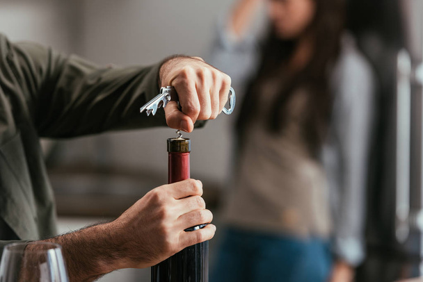 Selective focus of man opening wine bottle and worried wife at background - Photo, Image