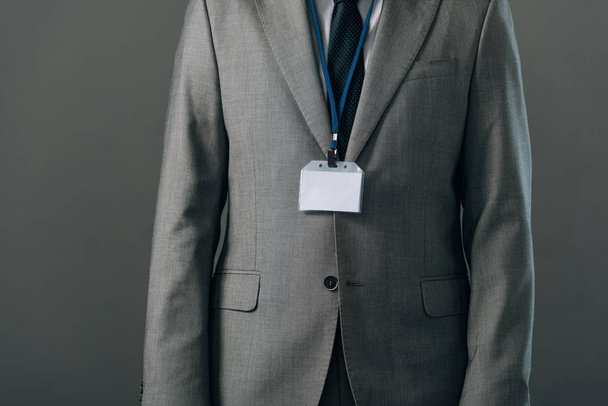 Cropped view of man in suit with badge isolated on grey - Foto, imagen