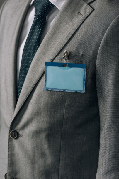 Cropped view of man with badge on grey suit - Photo, Image
