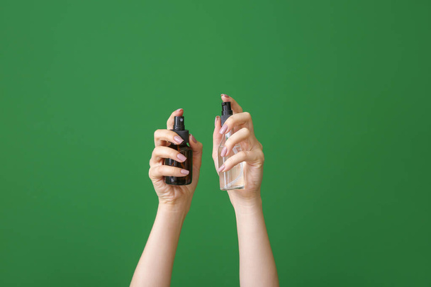Női kéz különböző kozmetikai termékek palackban színes háttér - Fotó, kép