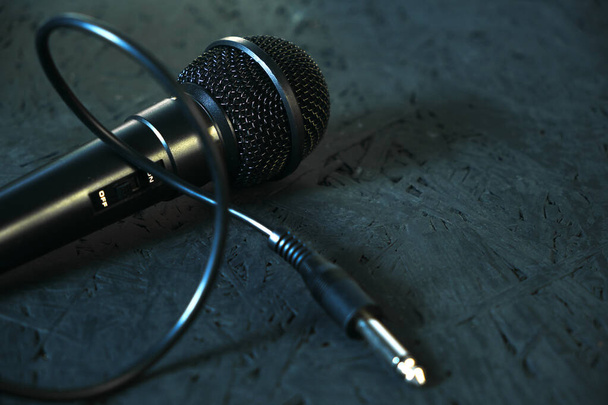 Black microphone dropped to the black wooden floor.Musical instrument for singing and karaoke. - Zdjęcie, obraz