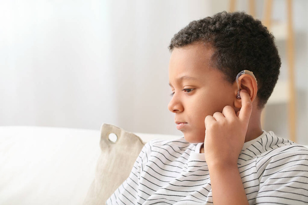 Kleine Afro-Amerikaanse jongen met gehoorapparaat thuis - Foto, afbeelding