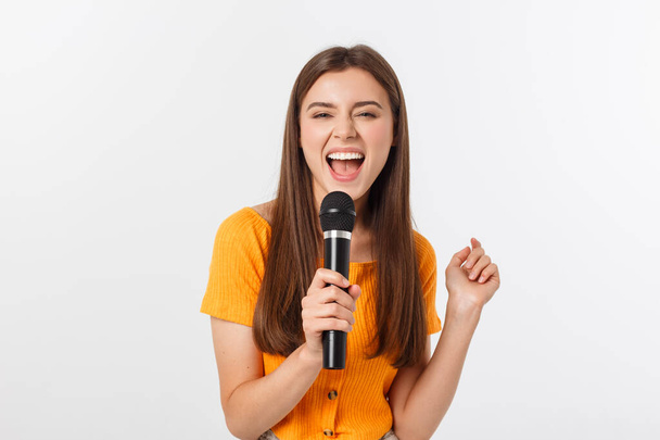 Young pretty woman happy and motivated, singing a song with a microphone, presenting an event or having a party, enjoy the moment - Photo, Image