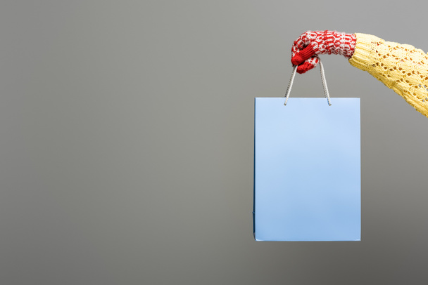 cropped view of woman in mitten holding shopping bag on grey background - Photo, Image