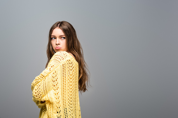 вид обиженной женщины в желтом свитере со скрещенными руками на сером фоне
 - Фото, изображение