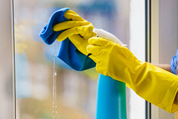 Gloved hand cleaning window rag and spray - 写真・画像