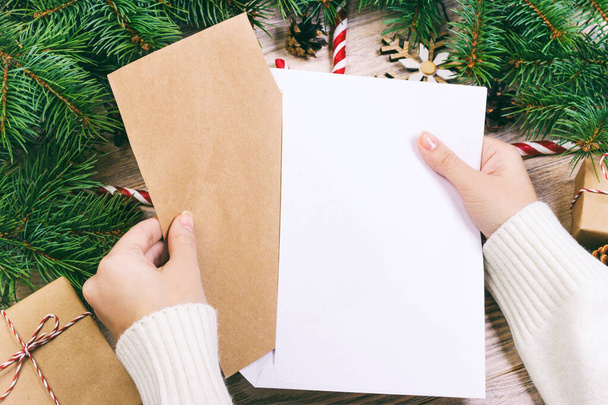 Руки с блокнотом и конверт для письма. Девушка готова послать письмо с пожеланиями Санта-Клаусу. Toned
 - Фото, изображение