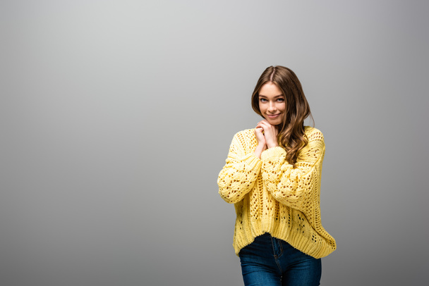 smiling shy woman in yellow sweater on grey background - Фото, изображение