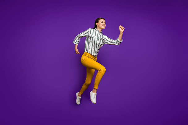 Full size profile photo of crazy beautiful lady jumping high rushing to finish line competitive sportswoman wear striped shirt yellow trousers isolated purple color background - Foto, afbeelding
