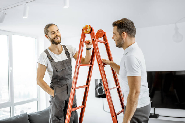 Двое рабочих разговаривают во время ремонта дома
 - Фото, изображение