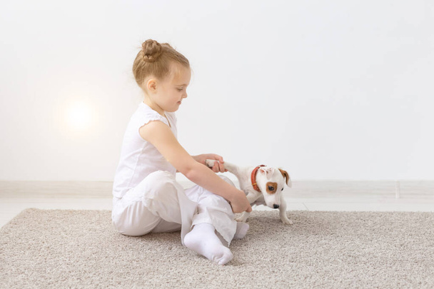 Dogs, children and pets concept - little child girl sitting on the floor with cute puppy - Photo, Image