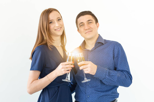 Hombre y mujer celebrando la fiesta de Navidad o Año Nuevo con copas de champán sobre fondo blanco
 - Foto, Imagen