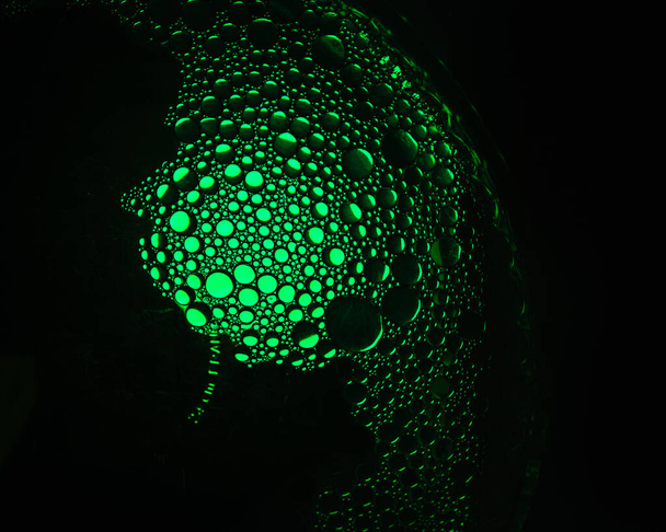 Yeşil renkli ampulle aydınlatılmış su ve zeytinyağı karışımından yeşil yağ damlacıkları - Fotoğraf, Görsel