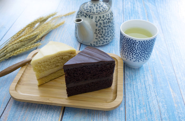 Ζεστό τσάι με κέικ σοκολάτας και κέικ γάλακτος στο μπλε ξύλινο πάτωμα - Φωτογραφία, εικόνα