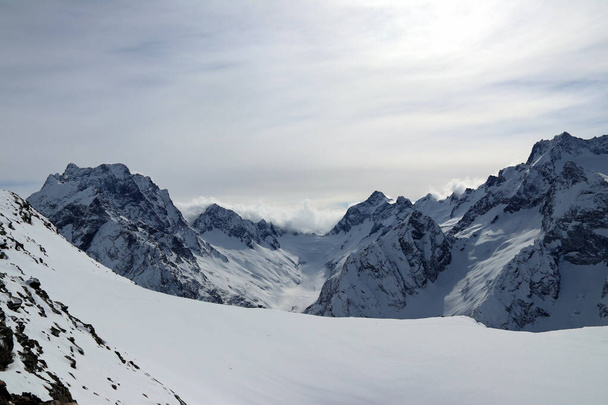 schneebedeckte Berge Gipfel in den Wolken blauer Himmel Kaukasus - Foto, Bild