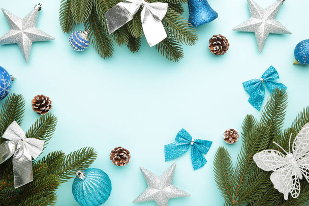 Fir tree branches with silver and blue christmas decoration on a mint background - Photo, Image