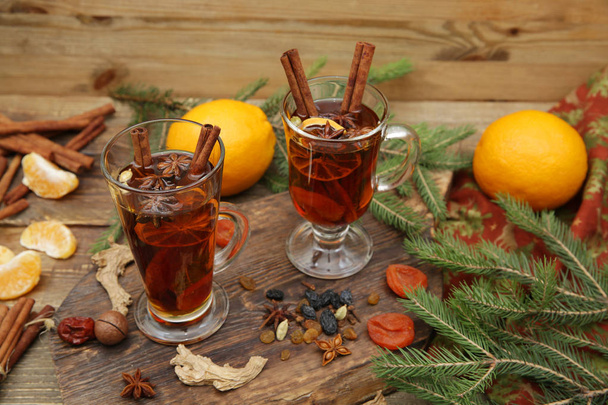 ζεστό ρόφημα ή τσάι με μπαχαρικά και μπαχαρικά σε ξύλινο φόντο με κλαδί ερυθρελάτης. Παραδοσιακό χειμερινό ποτό. Χριστουγεννιάτικη ιδέα, φόντο, πανό, μενού. - Φωτογραφία, εικόνα