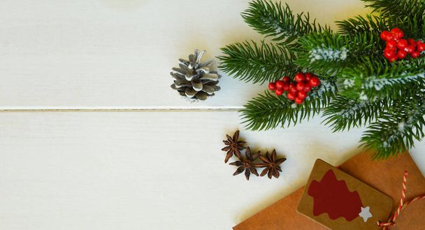 Christmas holiday background. Fir or pine branches, red berries, spices and gifts on rustic wooden table. Winter xmas holiday theme. Flat lay, top view, copy space. - Fotografie, Obrázek
