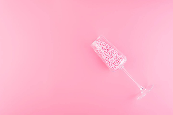 A glass of champagne is filled with decorative balls a pink past - Photo, image