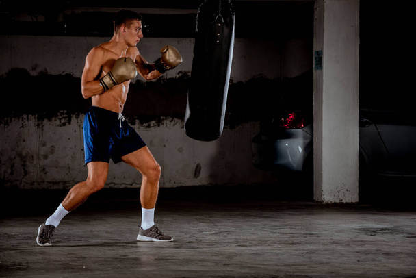 professionele bokser vechten en training in de fitnessruimte. Sterke, gespierde man opleiding en boksen - Foto, afbeelding