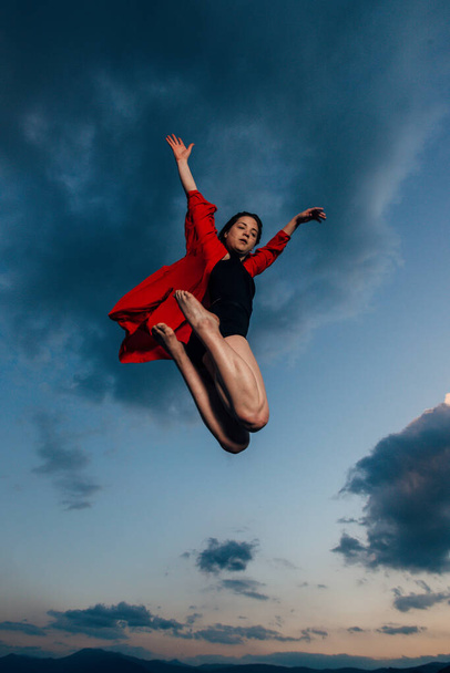 Flexible junge Frau in Ballettfigur vor blauem Himmel - Foto, Bild