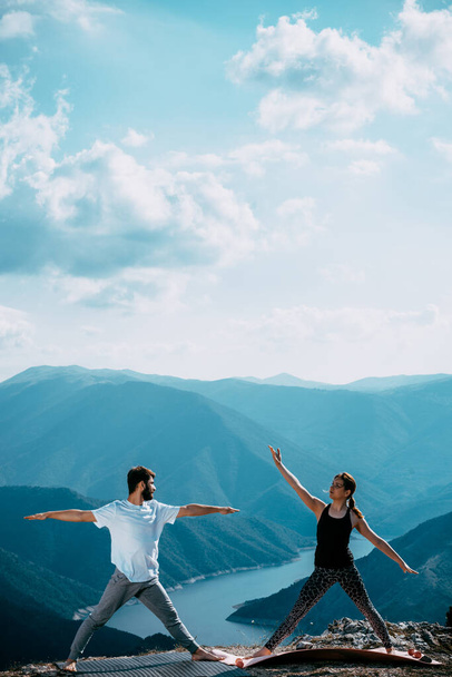 Найди равновесие, найди себя. Молодая пара занимается акро-йогой на природе - Фото, изображение