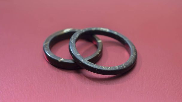 Handmade coconut rings with imperfections in red background. Artisan wedding ring bands symbolize love and union concept - 写真・画像