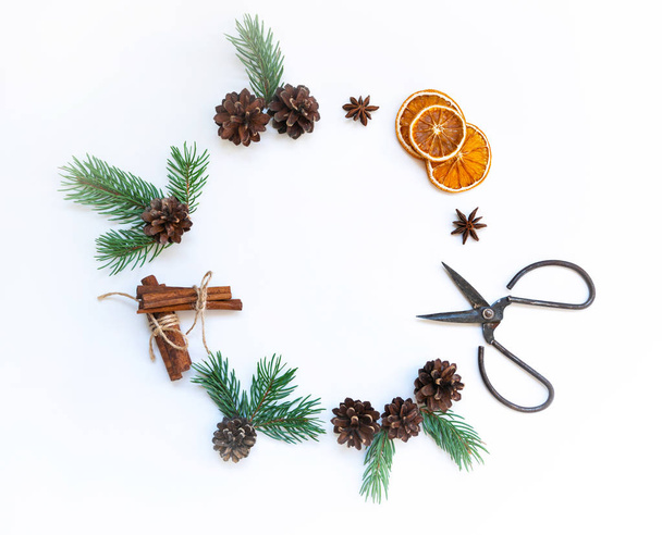 Christmas or new year wreath made with spruce branches, decoration, gingerbread, cinnamon, dry orange and decorative ornaments on light background. Christmas objects with empty copy space for text. - Фото, изображение