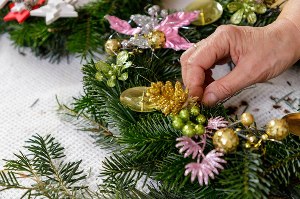 Hands of a woman decorate Christmas Advent wreath from fir twigs - Фото, изображение