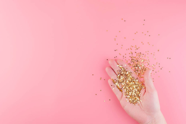 Female hand holds scattered gold stars confetti.  - Фото, зображення